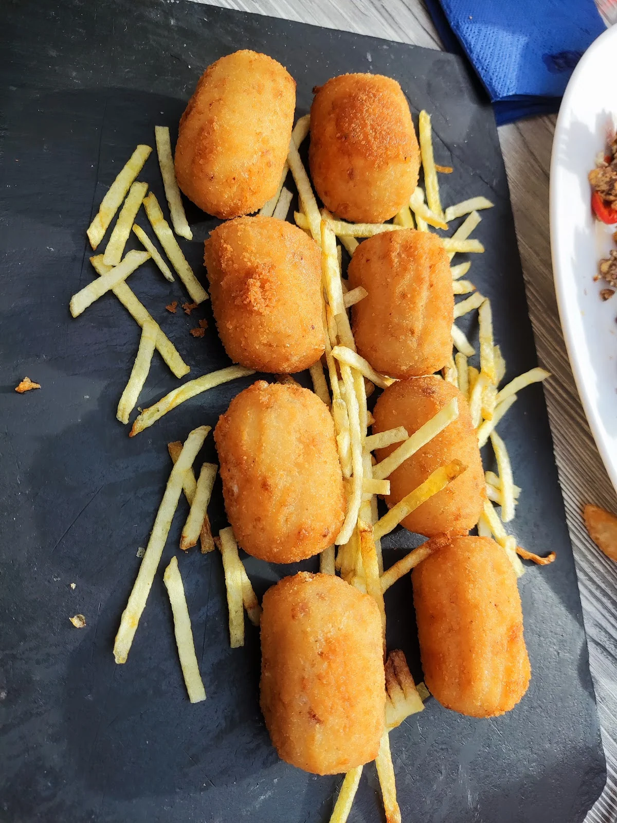 Croquetas caseras sobre patatas paja